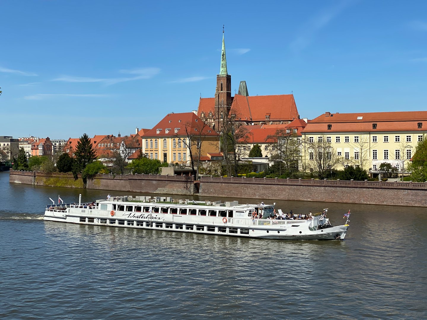 Passenger boat cruising a river past historic European buildings.