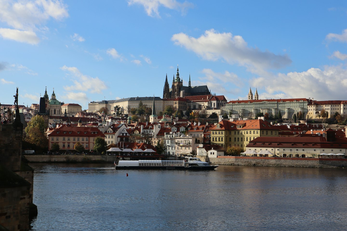 A passenger boat travels along a river by a historic city.