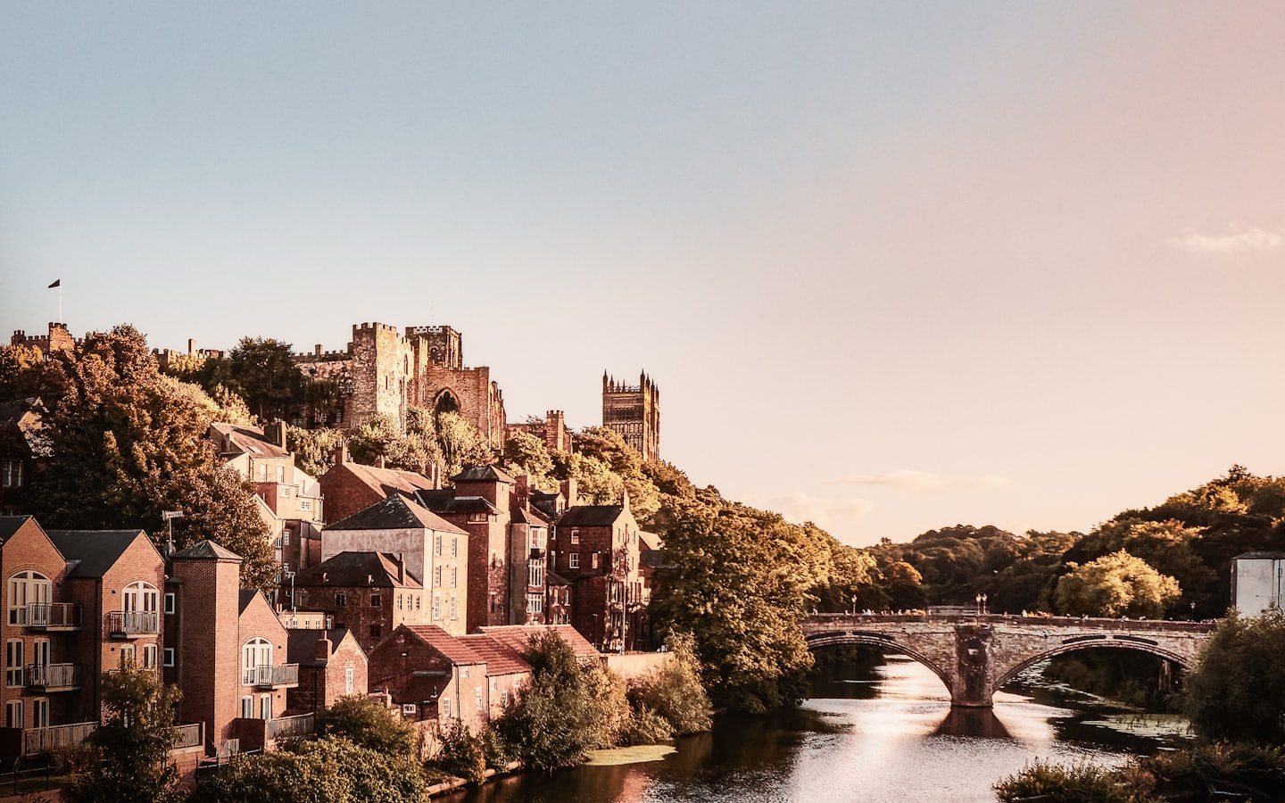A historic castle town overlooking a river with stone bridges.