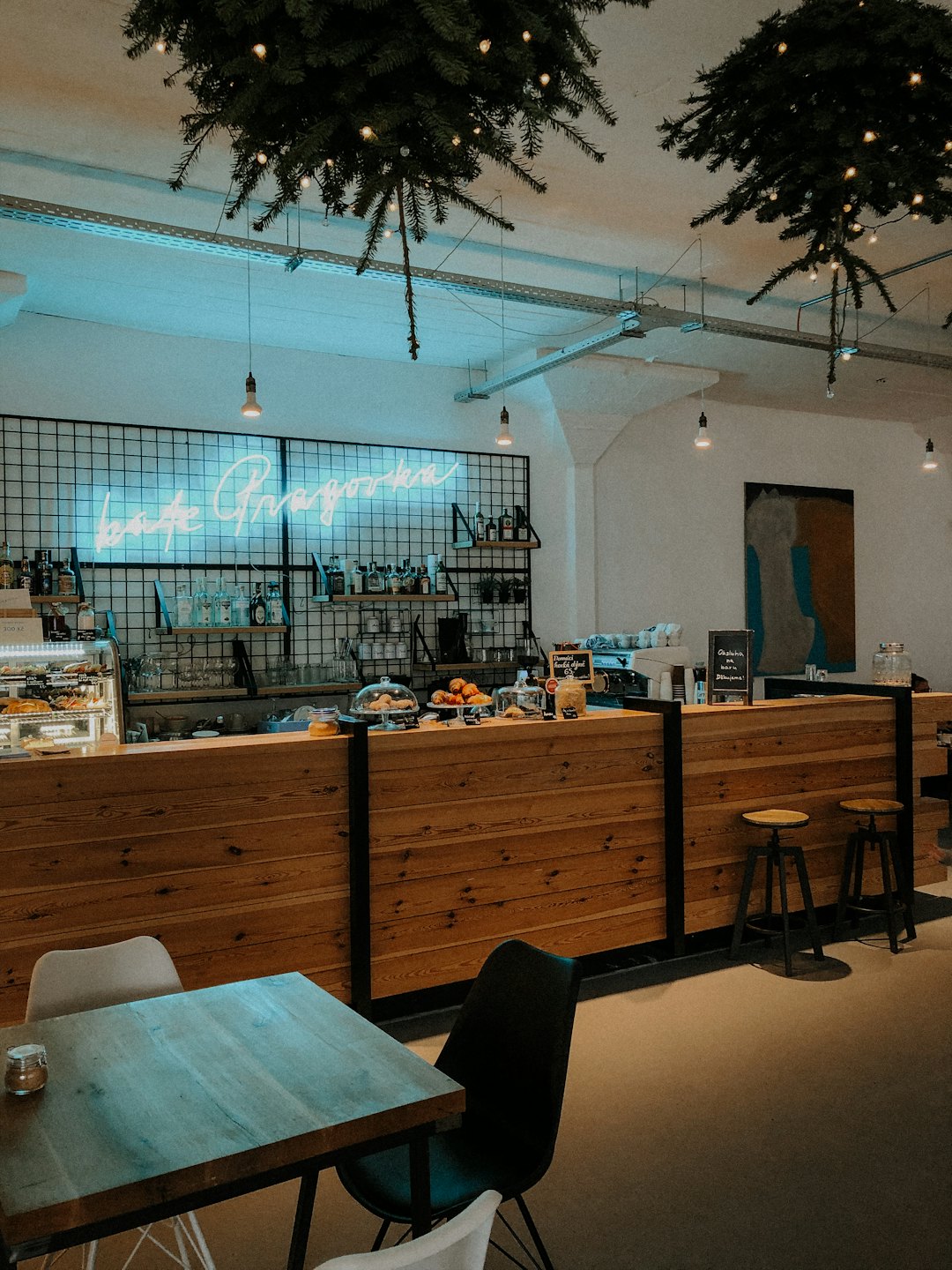 Modern cafe interior with wooden counter and neon sign.