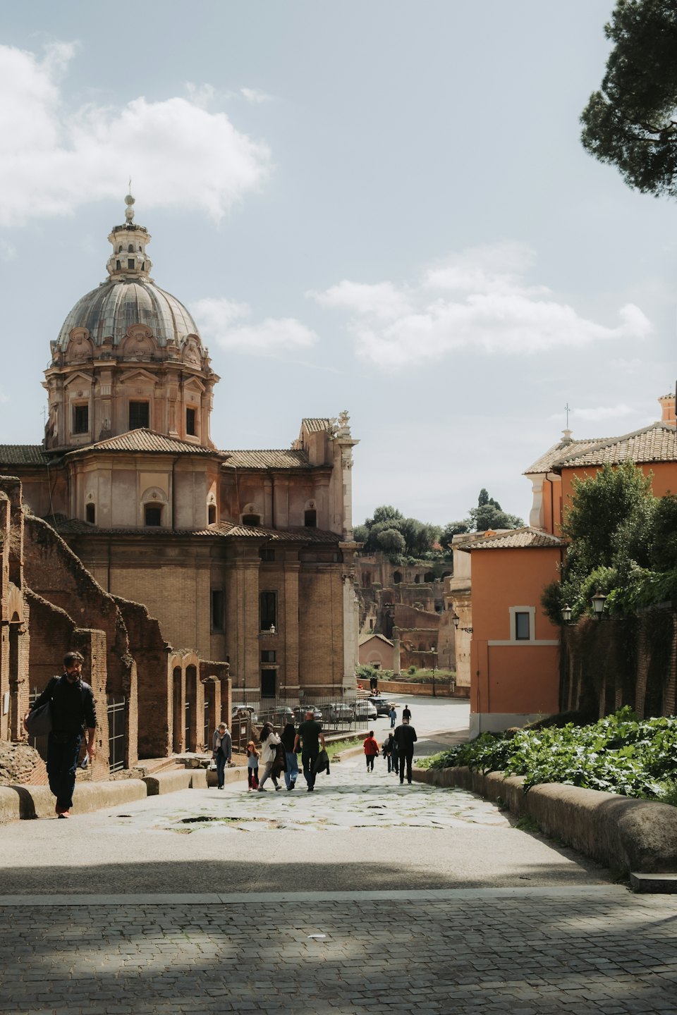 People walking down a historic cobblestone street by a church.